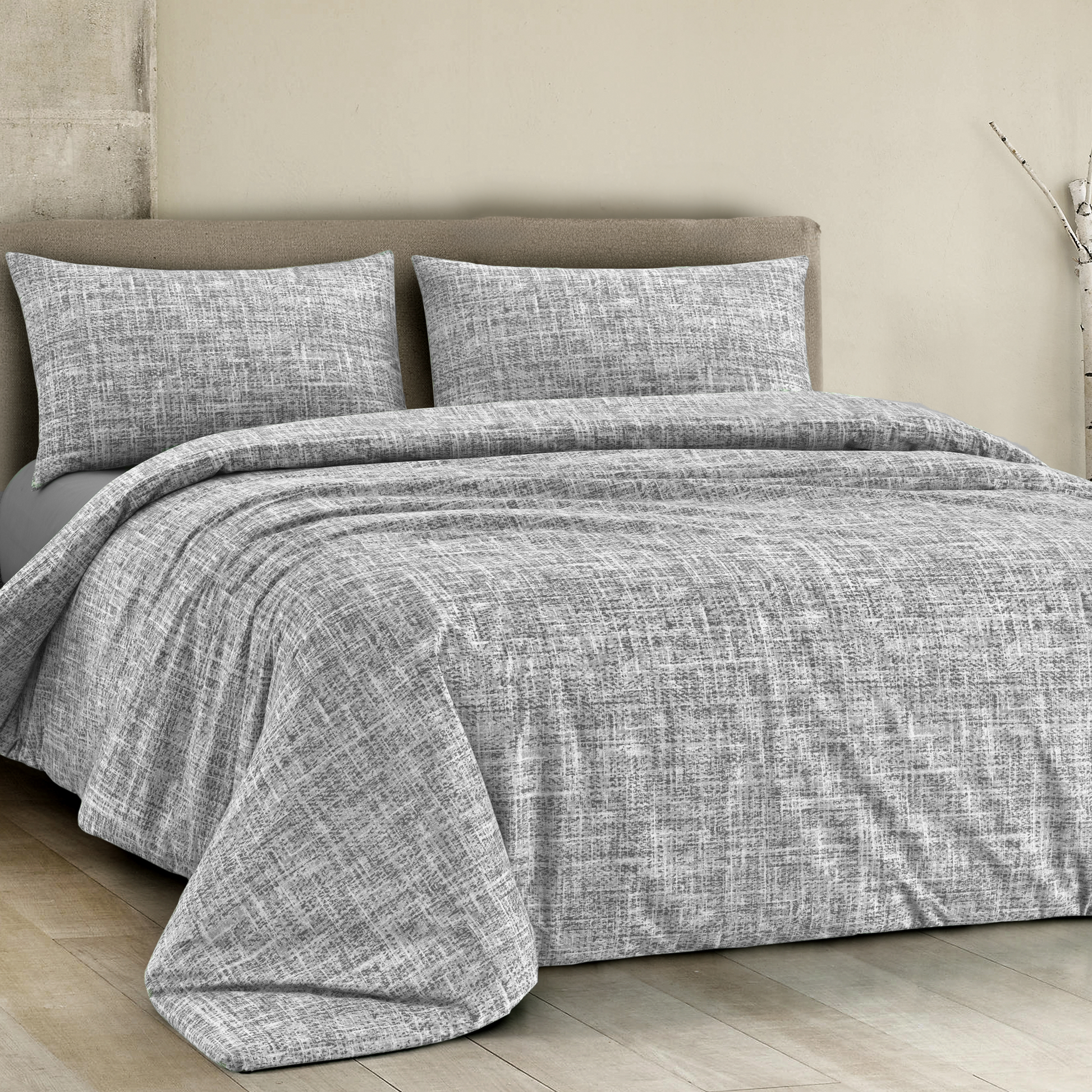 Copripiumino in cotone colore grigio con disegno geometrico, posizionato su un letto elegante