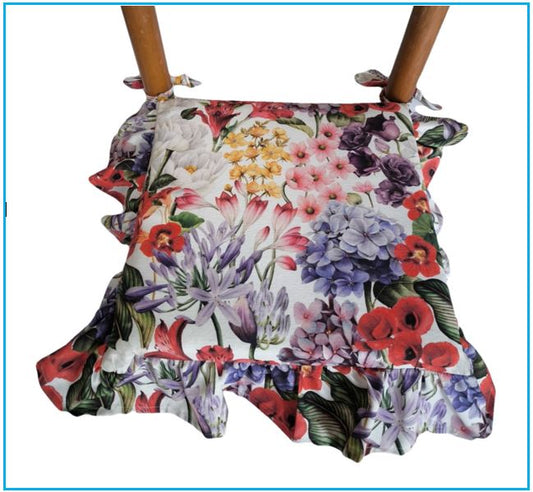 Cuscino con volant bianco posizionato su una sedia, usato come coprisedia decorativo.