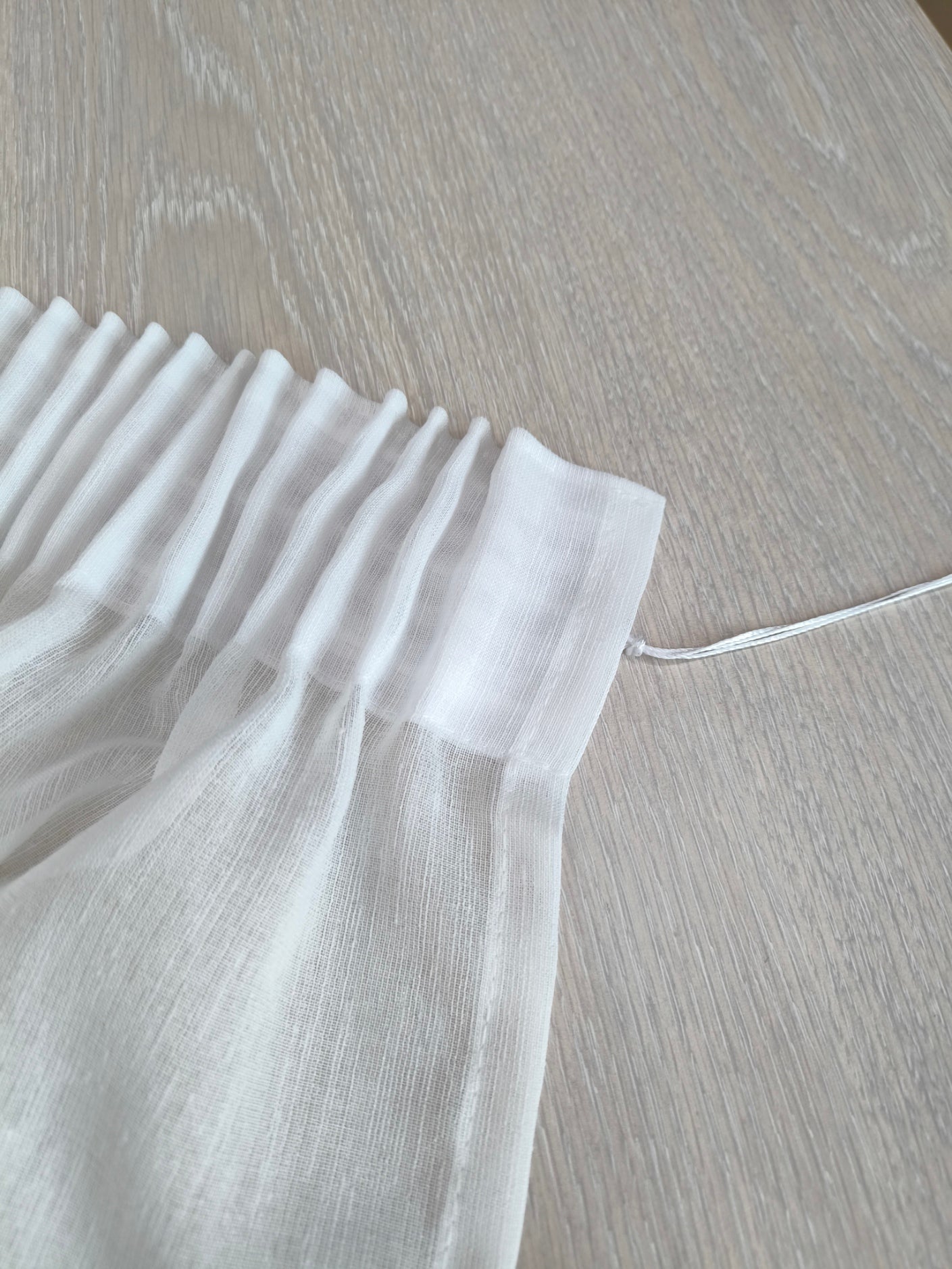 Dettaglio dell’arricciatura superiore della tenda bianca, che mostra il pieghettato elegante e uniforme.