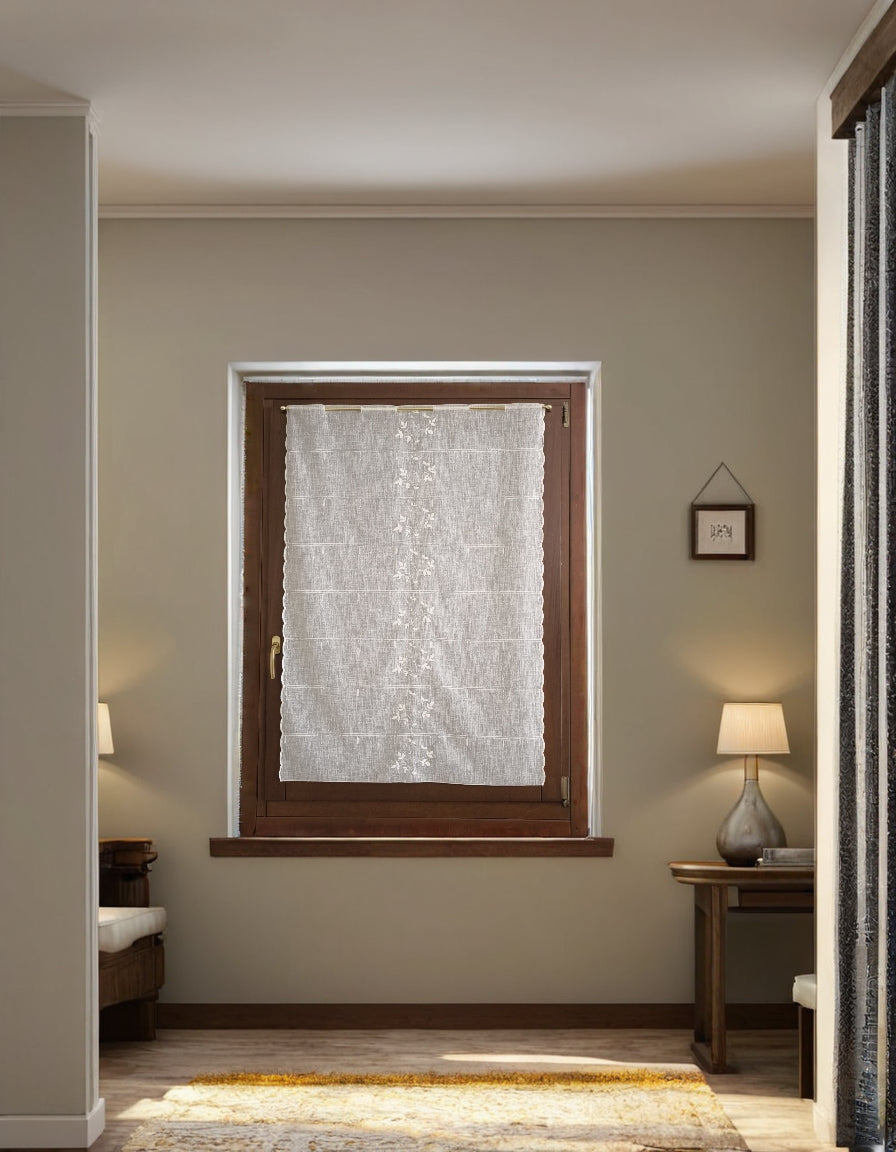 tenda a vetro bianca con ricamo centrale a rami e foglie, appesa a una finestra in salotto, tessuto leggero e trasparente effetto lino che filtra la luce naturale