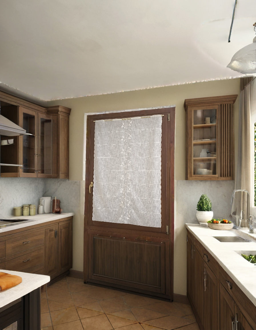 tenda a vetro bianca con ricamo centrale a rami e foglie, appesa a una porta in cucina, tessuto leggero effetto lino che lascia entrare luce naturale