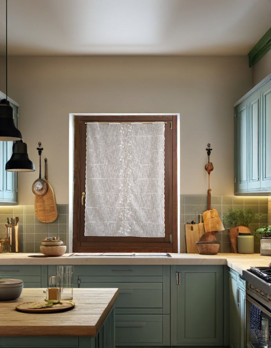 tenda a vetro bianca con ricamo centrale a rami e foglie, appesa a una finestra in cucina, tessuto trasparente effetto lino che illumina l’ambiente