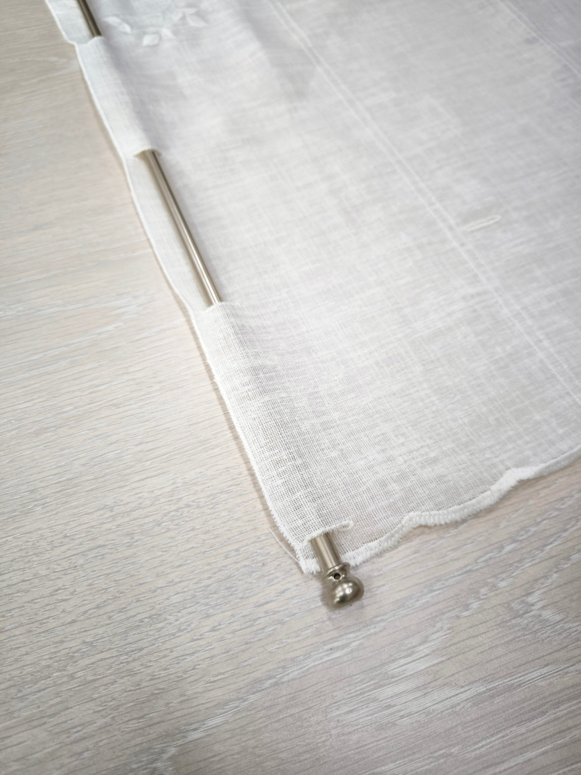 particolare della parte superiore della tenda a vetro con occhielli rinforzati per inserire il bastoncino e appenderla facilmente