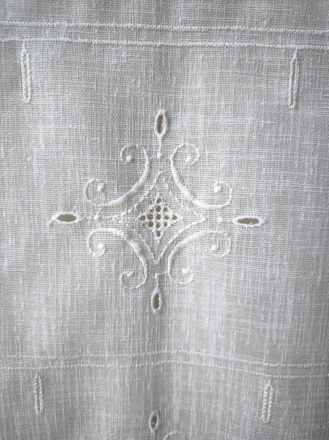 Dettaglio del ricamo con intaglio su tenda a vetro, motivo elegante