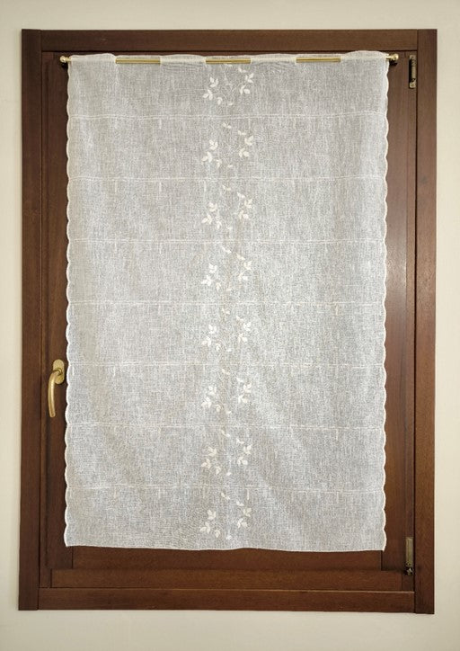 tenda a vetro bianca con ricamo centrale in rilievo a rami e foglie, appesa a una finestra, tessuto effetto lino leggero e trasparente
