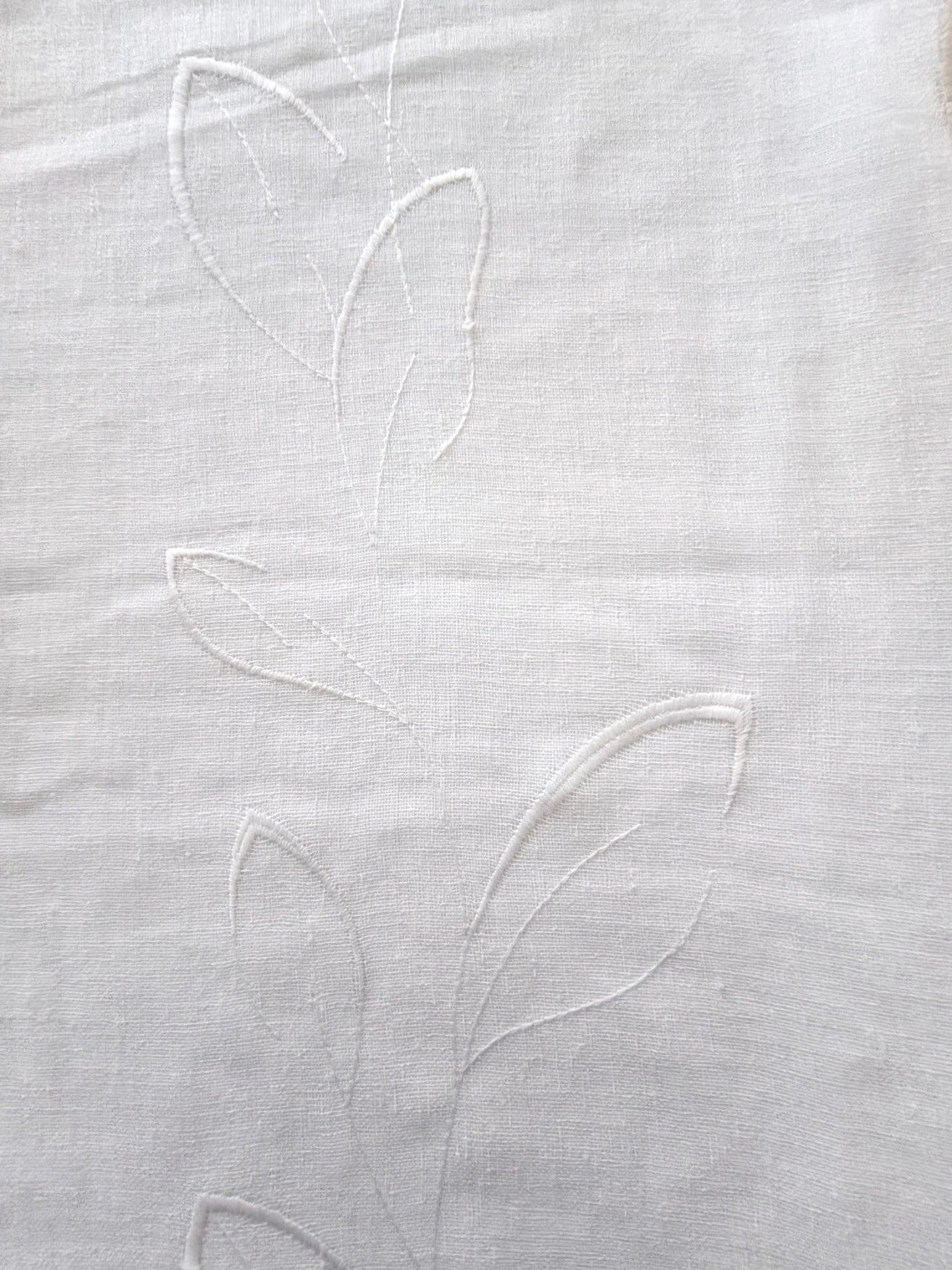 Dettaglio di tessuto effetto lino per tende con ricamo a foglia stilizzata tono su tono, ideale per decorazione d’interni eleganti